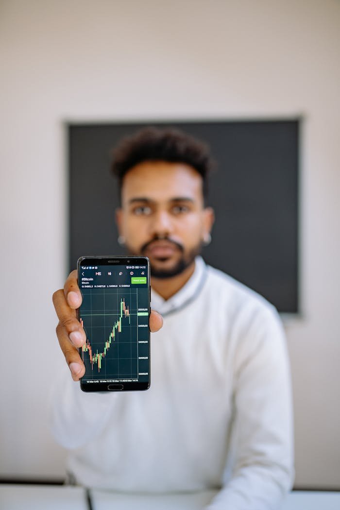 Man holding smartphone with stock market chart, focusing on financial growth.